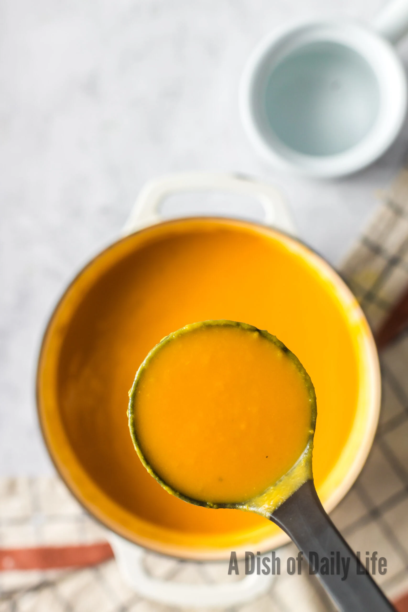 A ladle scooping soup out of the pot.