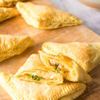 hand pies laid out on a cutting board with one cut in half to show filling