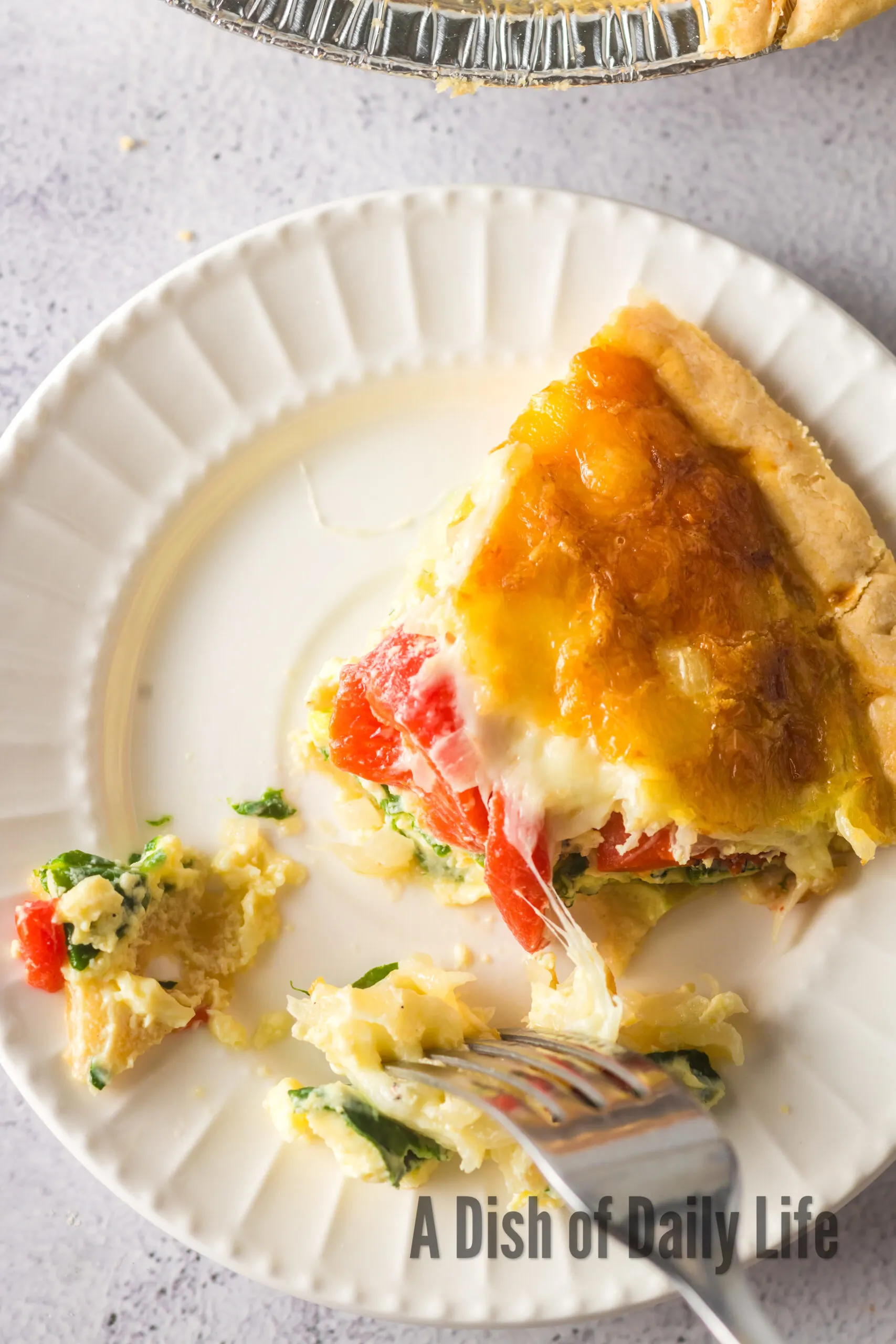 Top view looking down at quiche on a plate with a fork