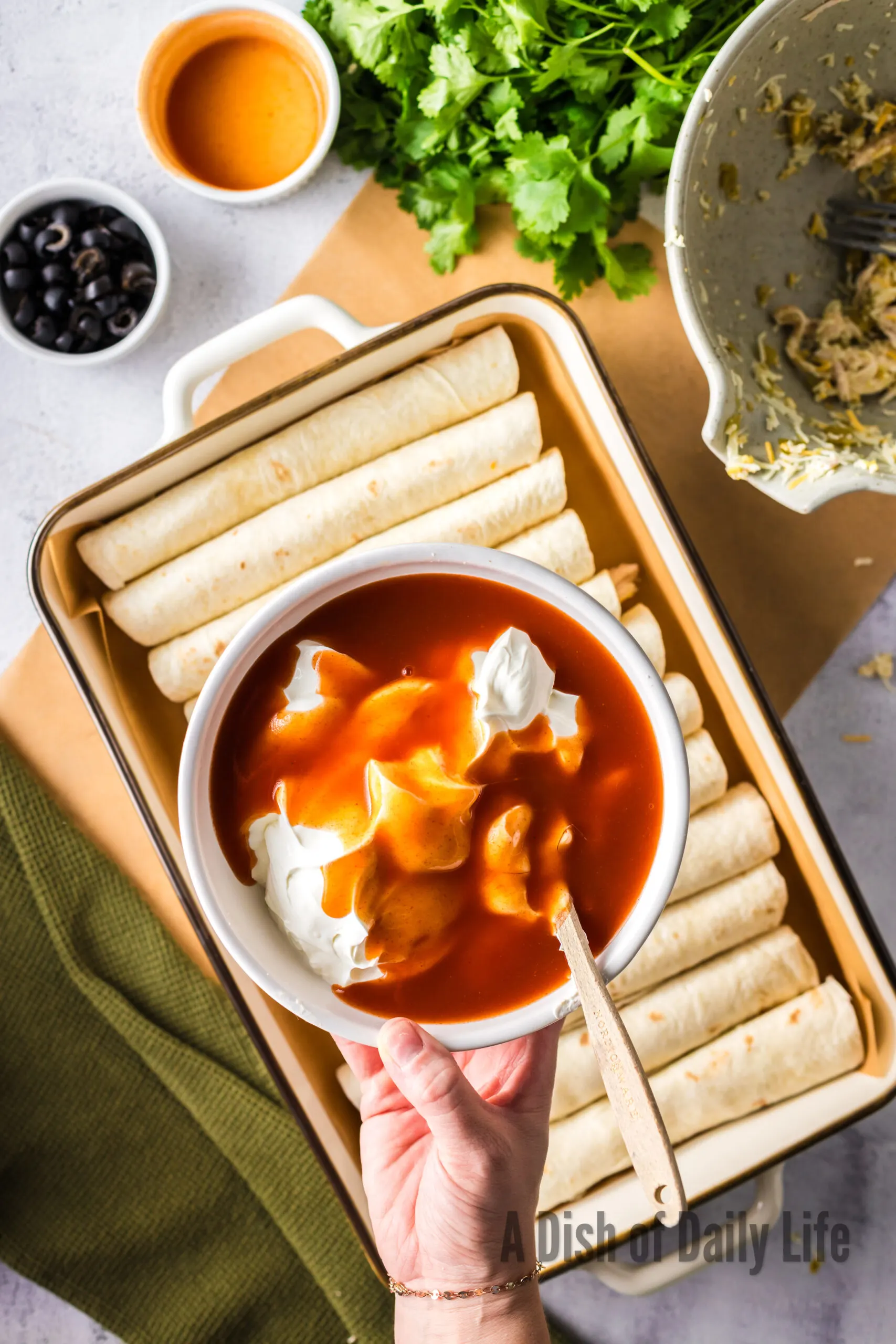 sour cream and red enchilada sauce in a bowl being mixed together