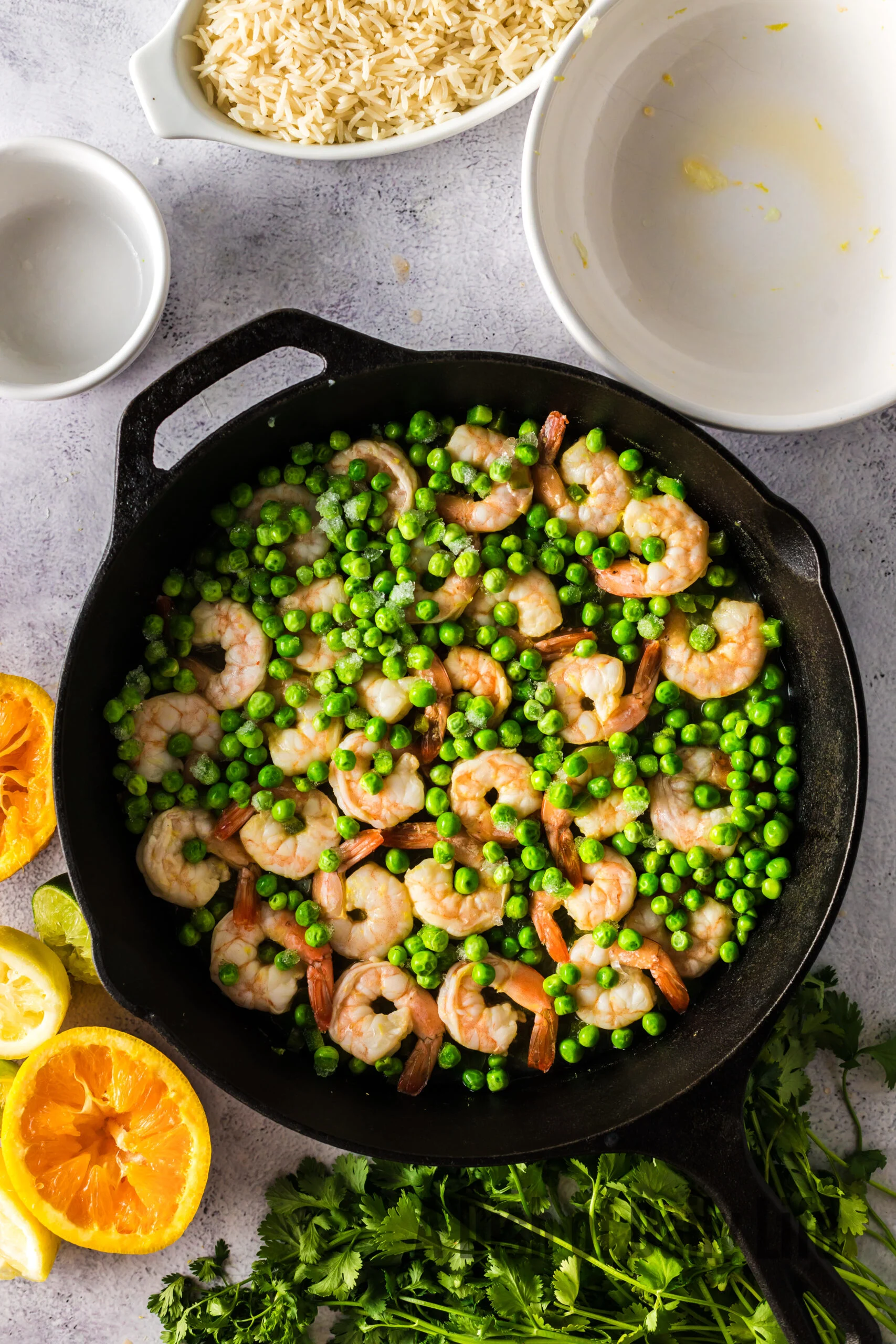 cooked shrimp in a skillet with peas added on top.