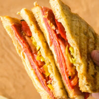 hand holding cut pepperoni panini to show yummy fillings