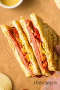 hand holding cut pepperoni panini to show yummy fillings