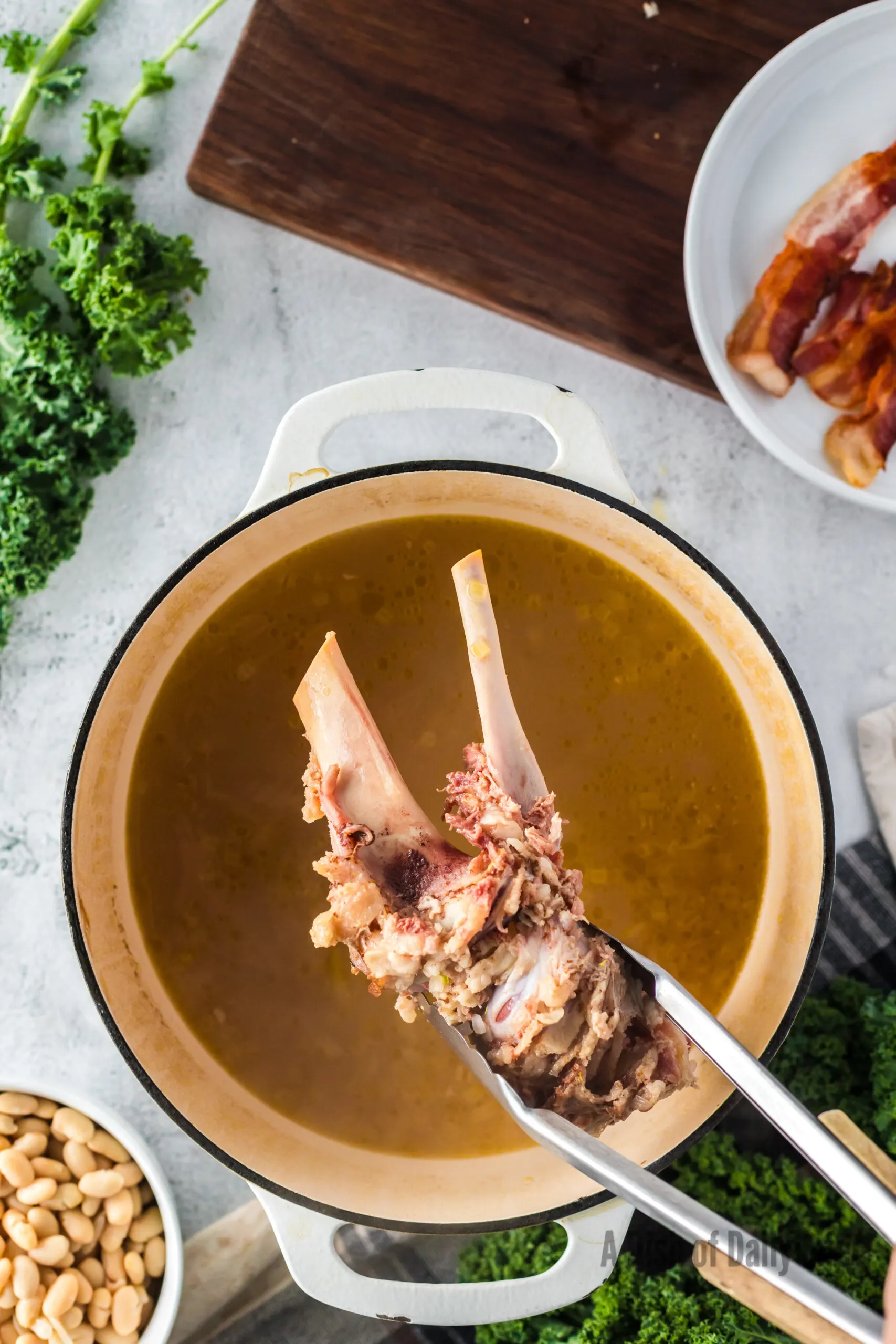 Removing cooked ham bone from pot of soup.