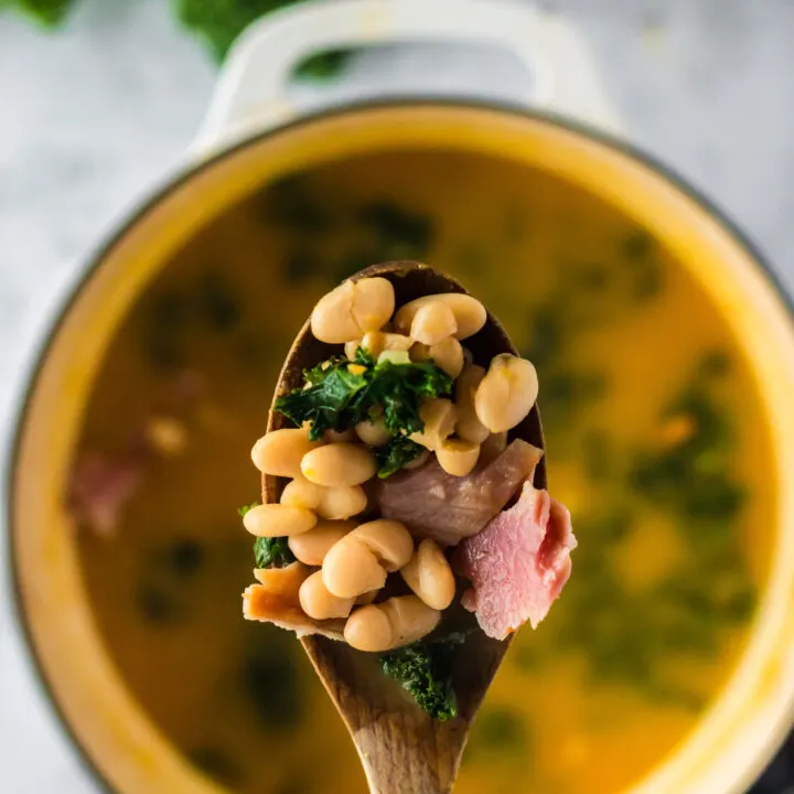 Wooden spoon scooping a portion of soup out of pot.