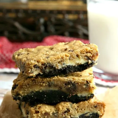 Oreo Chocolate Chip Cheesecake Bars...a melt in your mouth good dessert recipe! Cheesecake filling sandwiched in between Oreo cookie crumbles and chocolate chip cookie dough