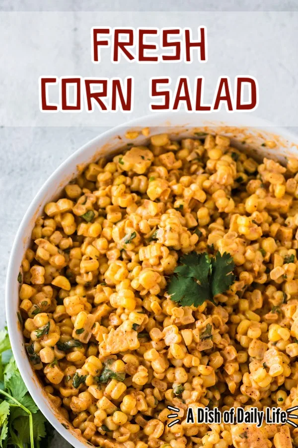 Main image for fresh corn salad. Salad in a large serving bowl with a sprig of cilantro on top.
