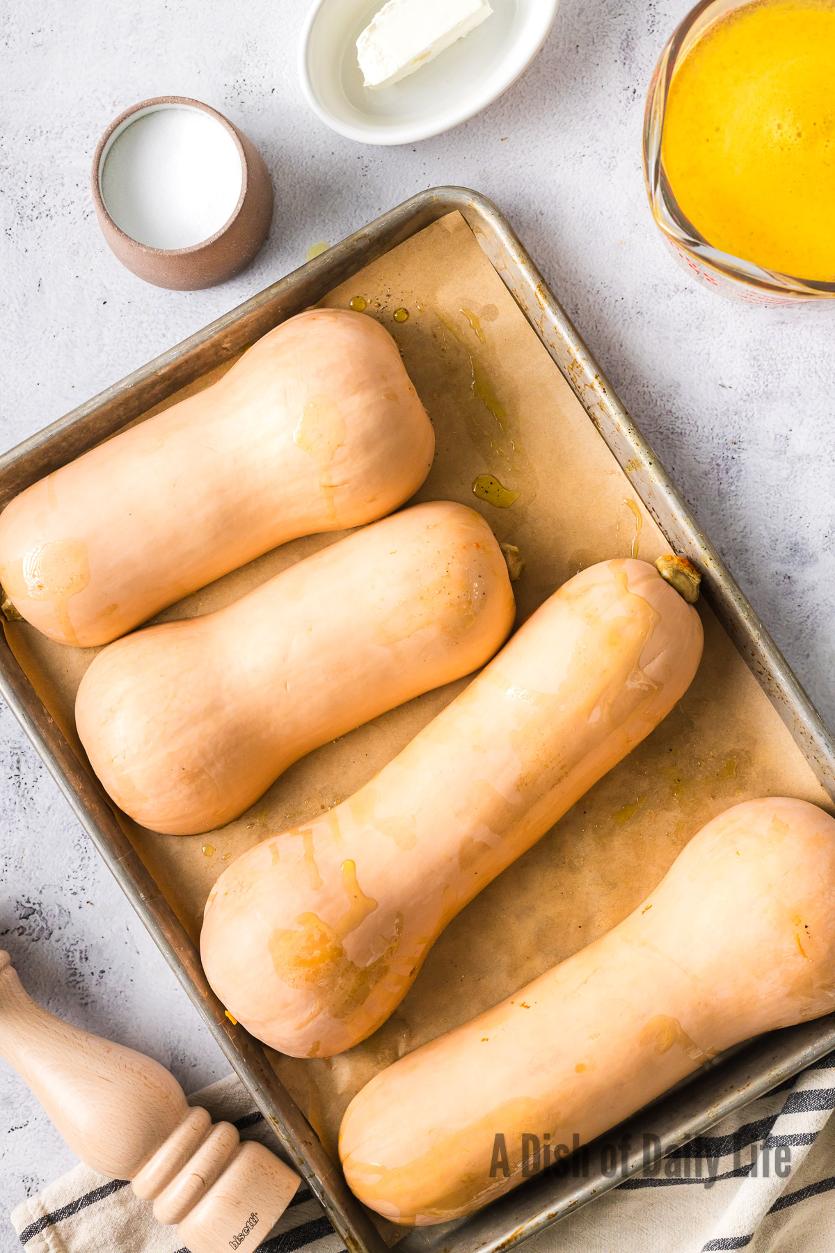 4 halves of butternut squash facedown on a lined baking sheet