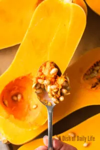 scooping seeds out of a sliced open squash