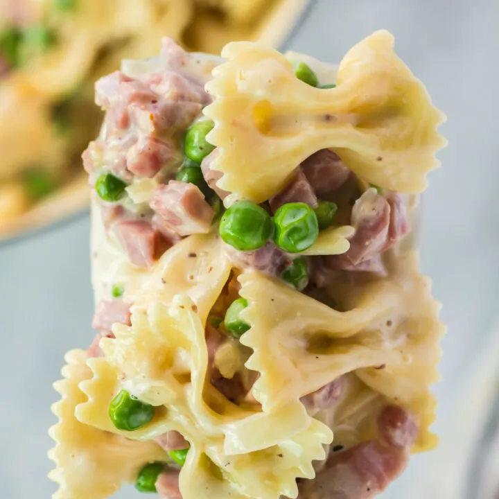 wooden serving spoon full of creamy ham pasta mix