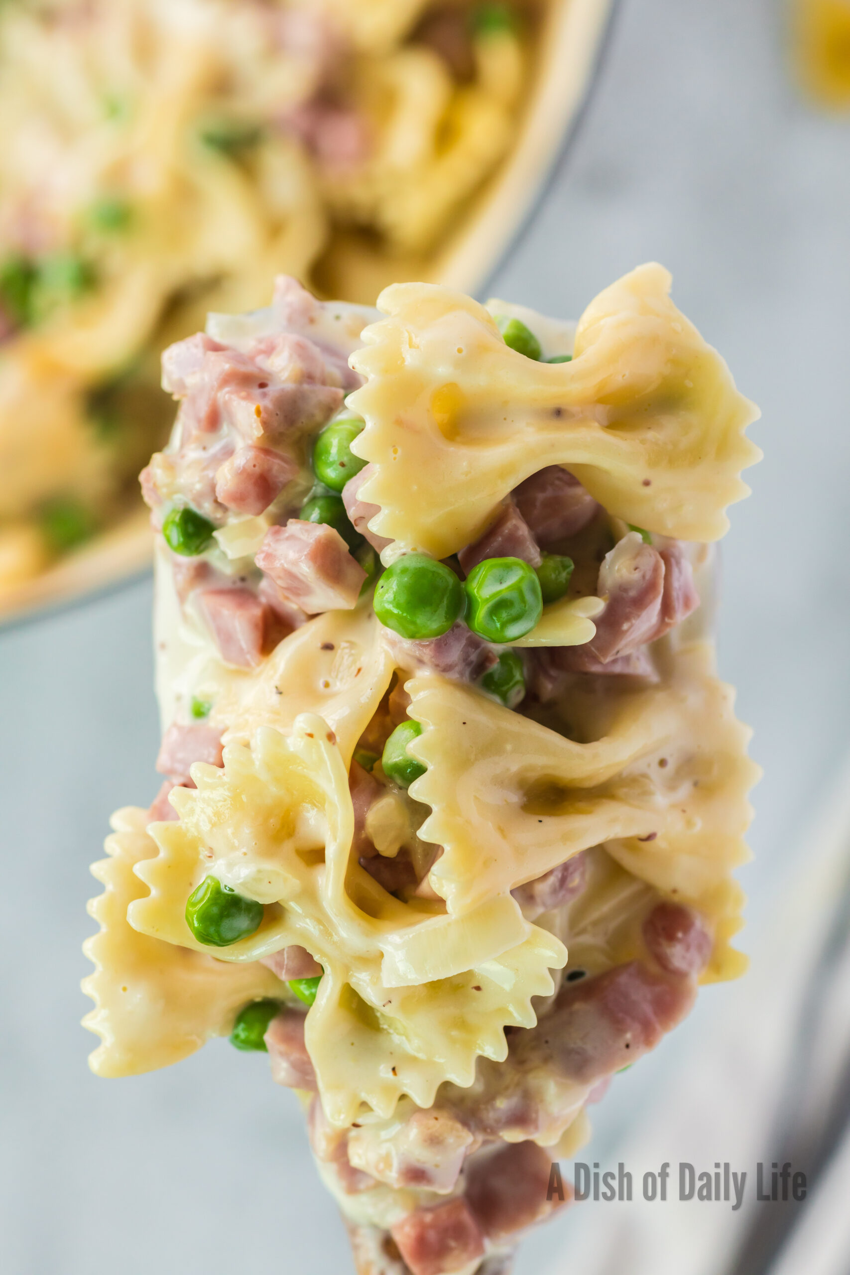 wooden serving spoon full of creamy ham pasta mix