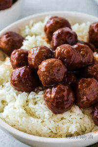 cranberry meatballs placed on top of a bowl of rice.