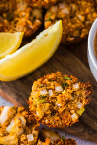 Zoomed in image of crab cake with lemon wedges on serving board.