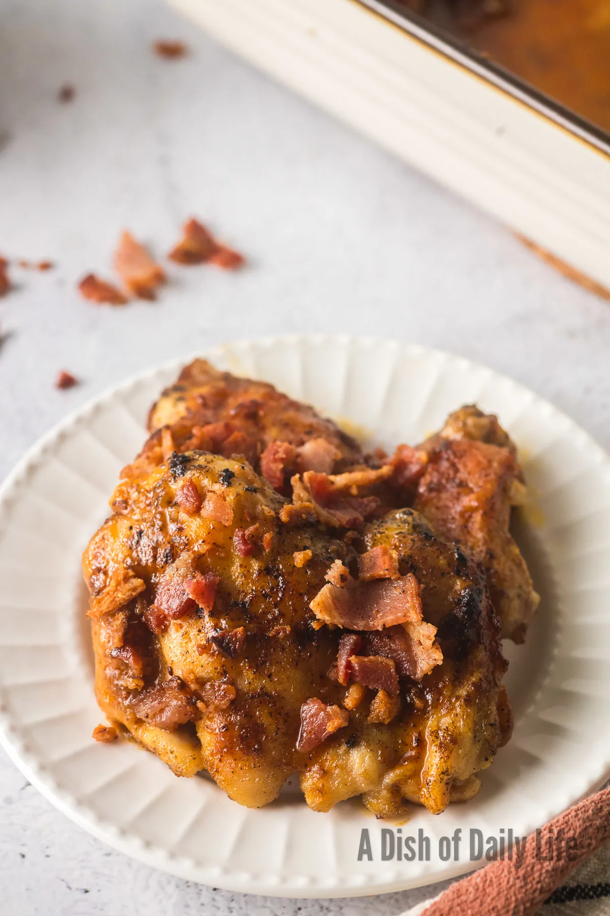 single cooked chicken thigh with bacon on plate