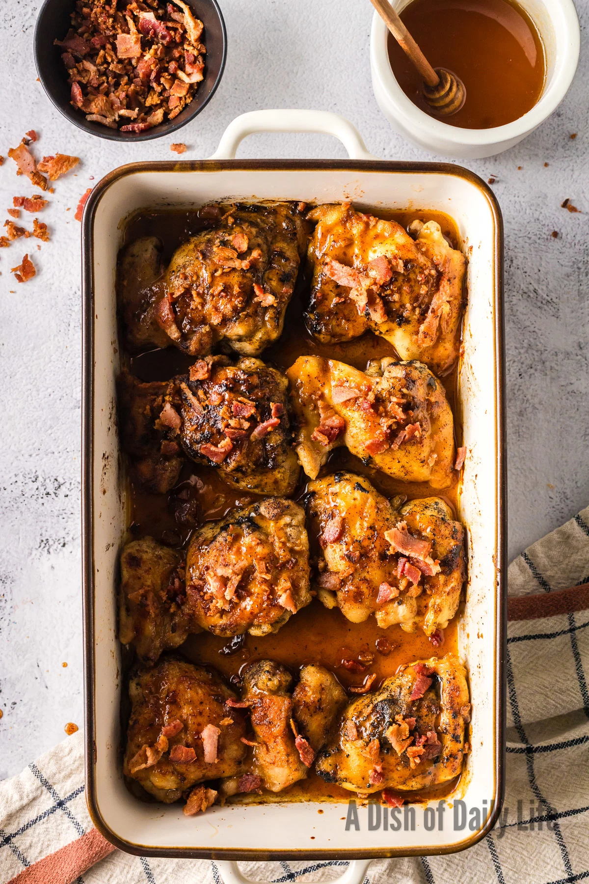 cooked thighs in casserole dish topped with crumbled bacon and honey mustard sauce.