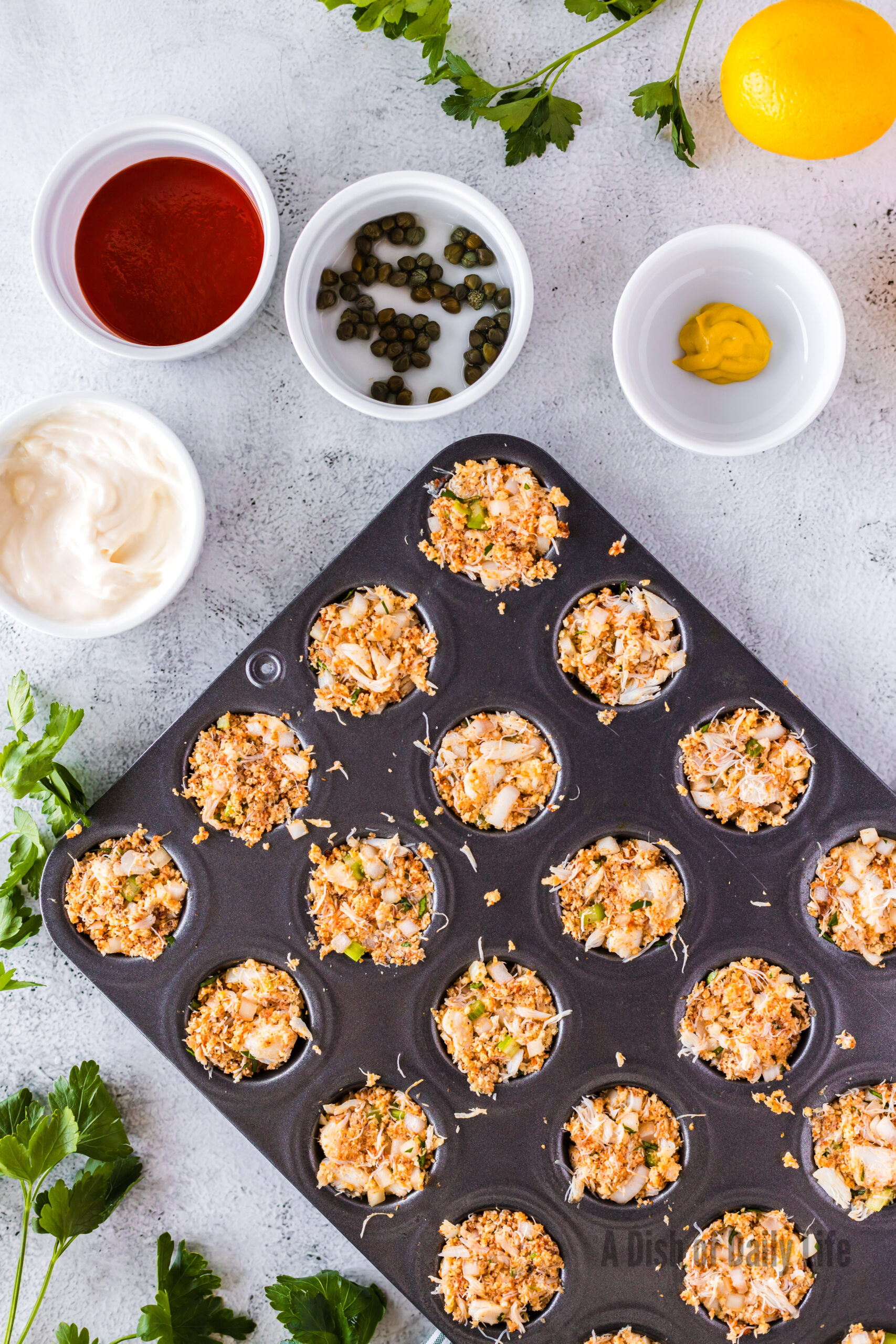 crab cakes pressed into mini muffin tin pan, unbaked