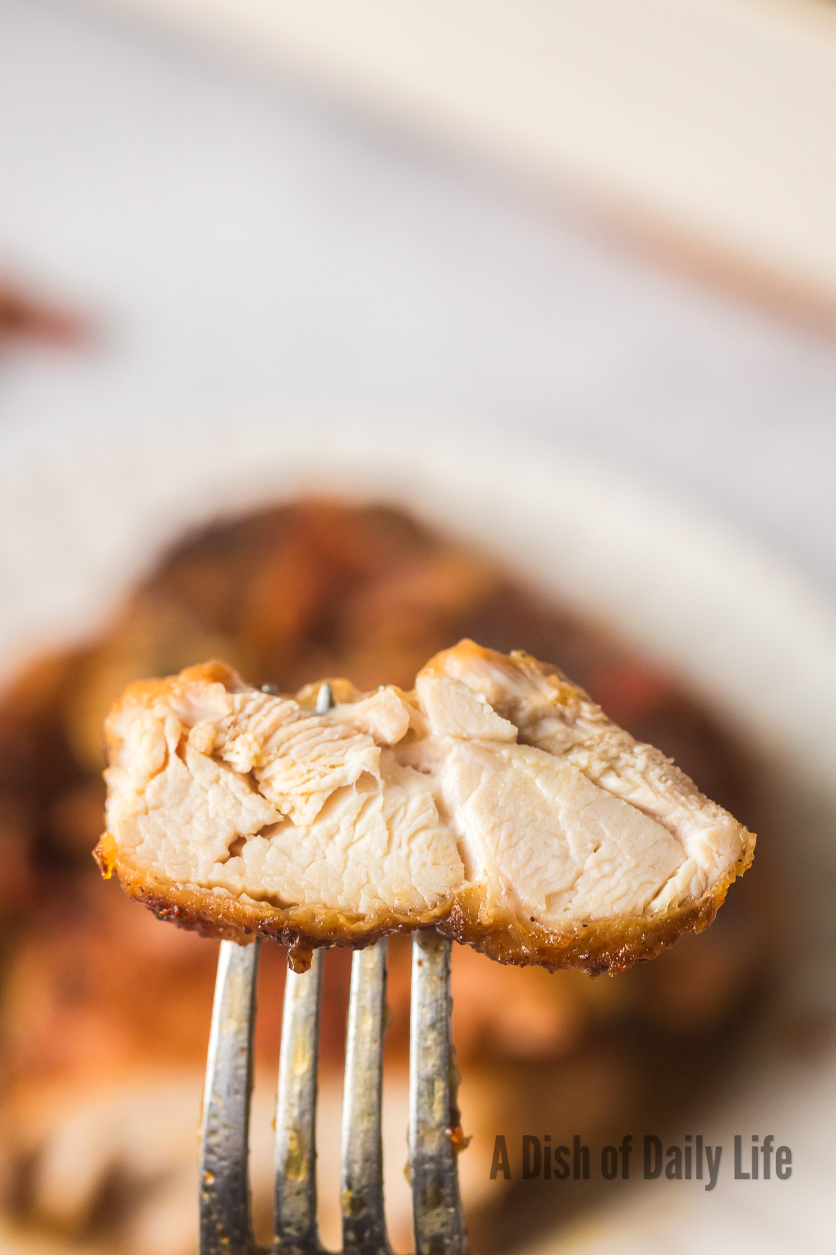 A slice of chicken thigh on fork to show how juicy and tender it is