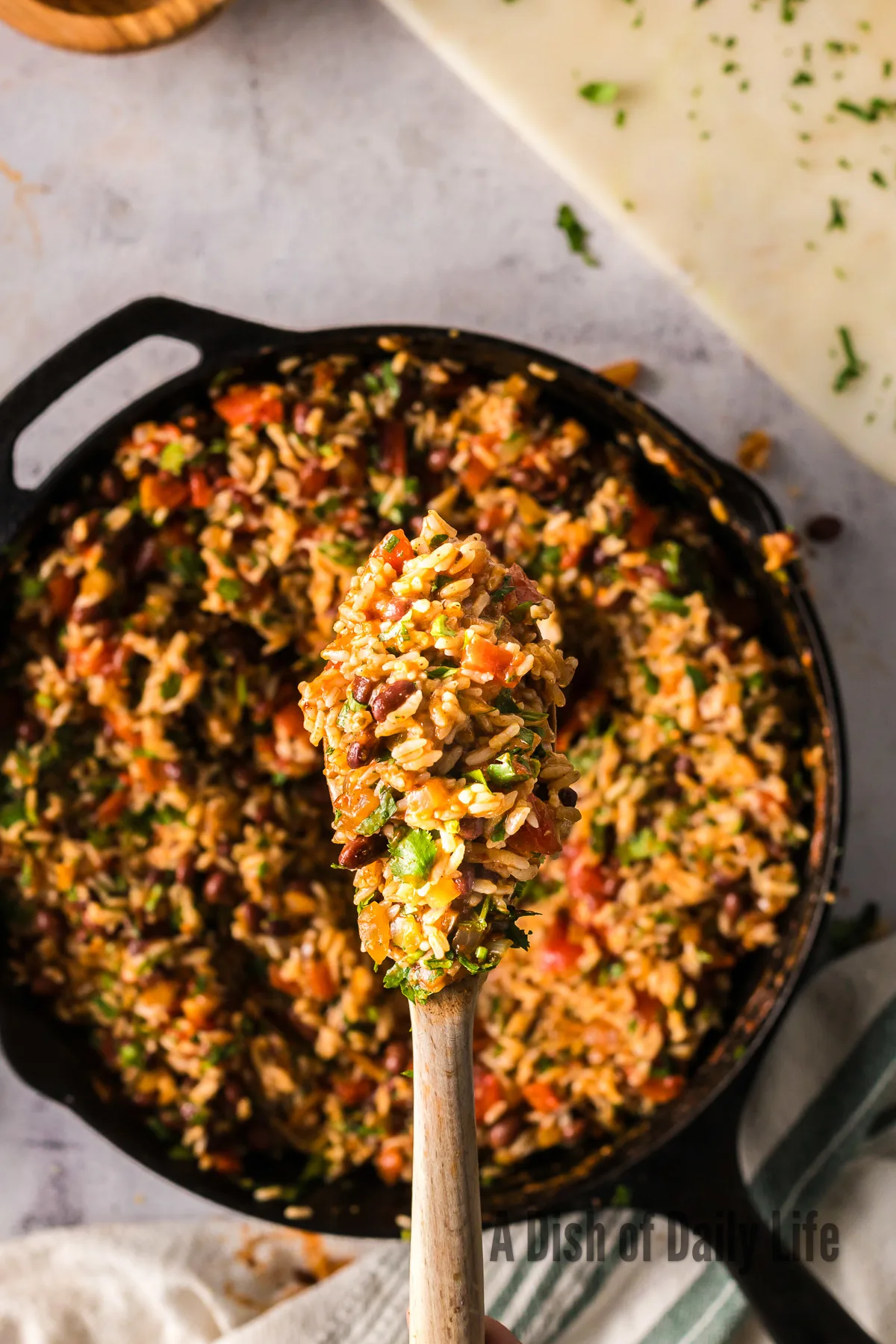 cooked rice mixture in a skillet with a wooden spoon scooping some up to show camera.