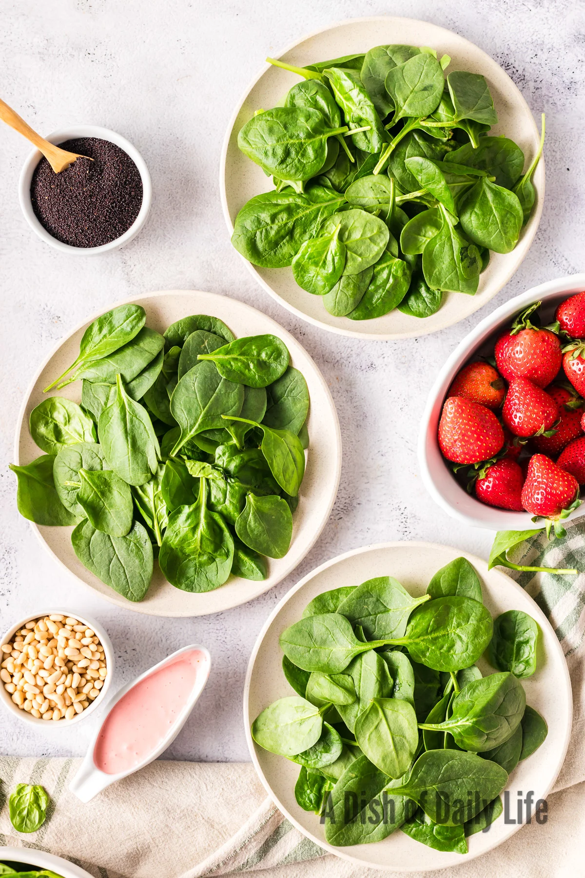 spinach leaves placed in 3 bowls to create the base of a salad