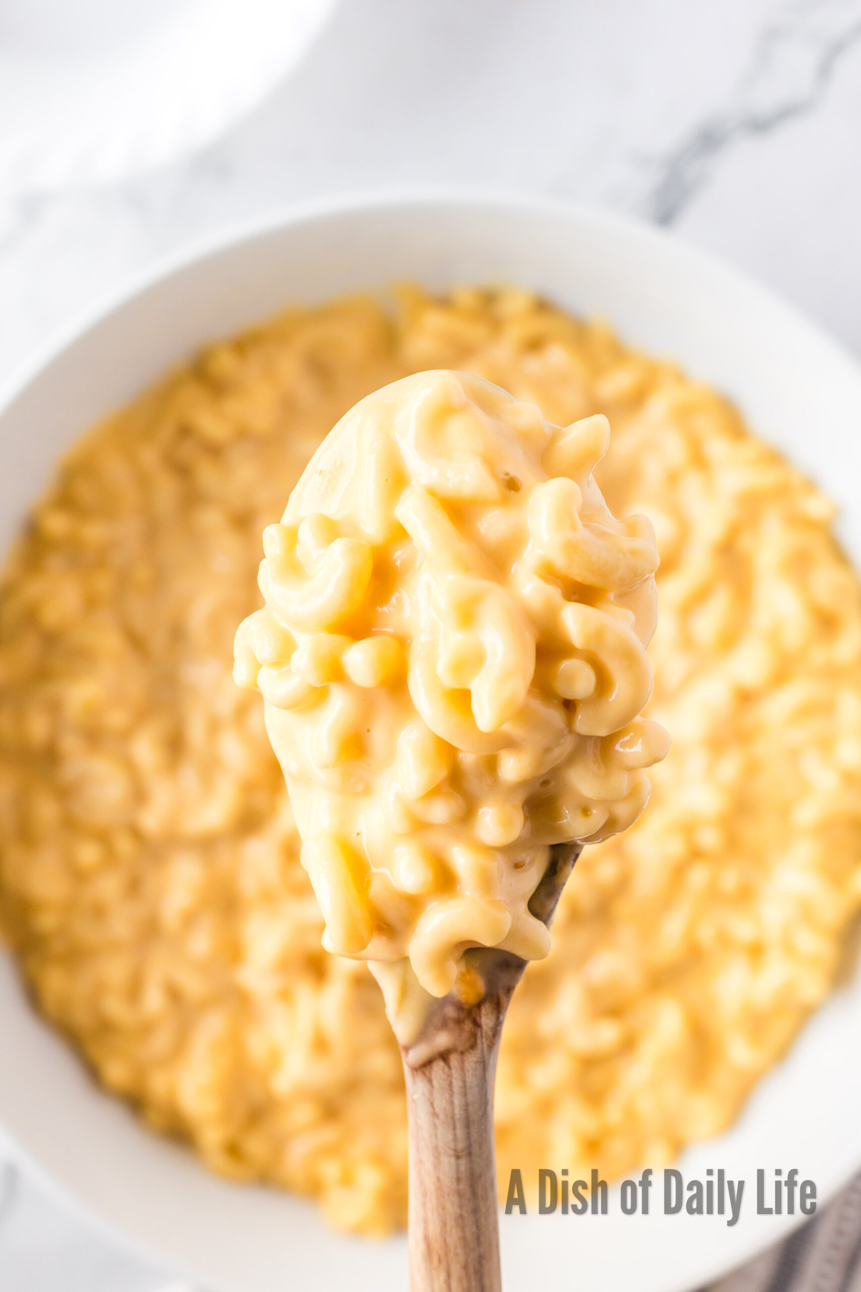 Creamy macaroni and cheese being scooped into a serving bowl