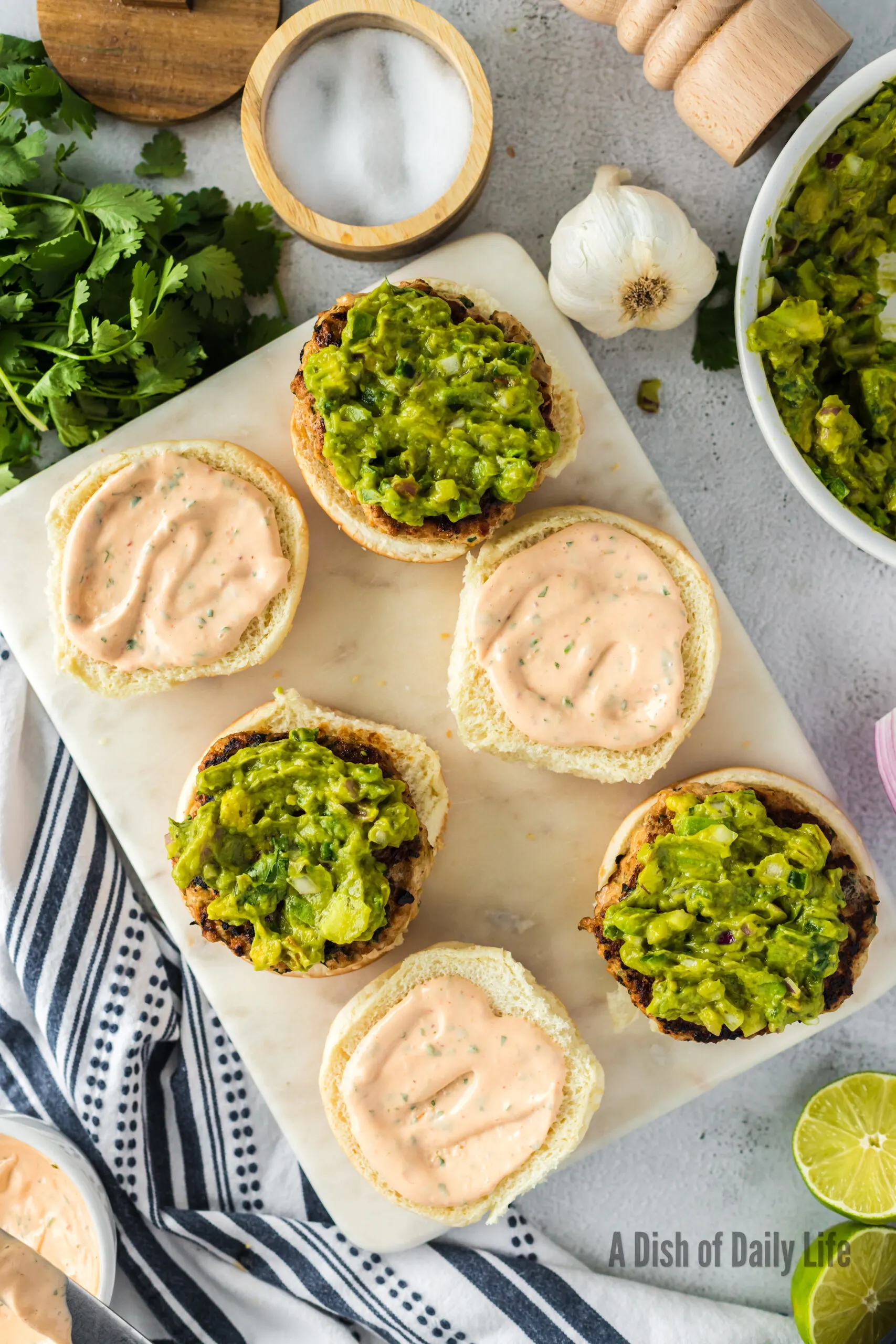 Buns laid open with chipotle mayo on top bun and patty with guacamole on bottom bun.