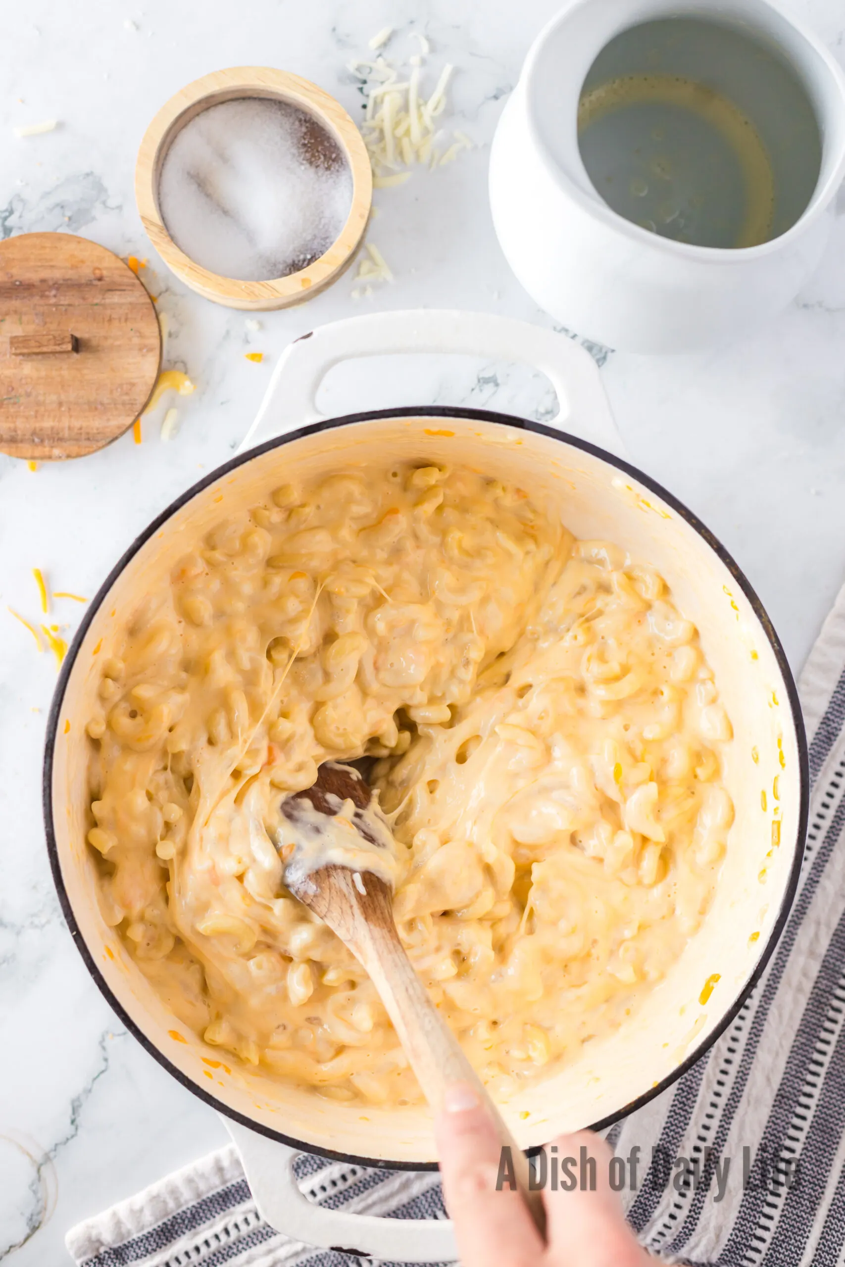 Cheese mixed up in macaroni in pot with a wooden spoon stirring