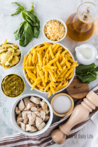 All ingredients for artichoke pesto pasta laid out on counter.