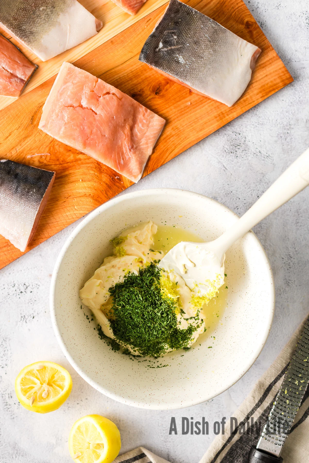 Mayonnaise, lemon zest, ginger paste, and cilantro in a bowl, unmixed.