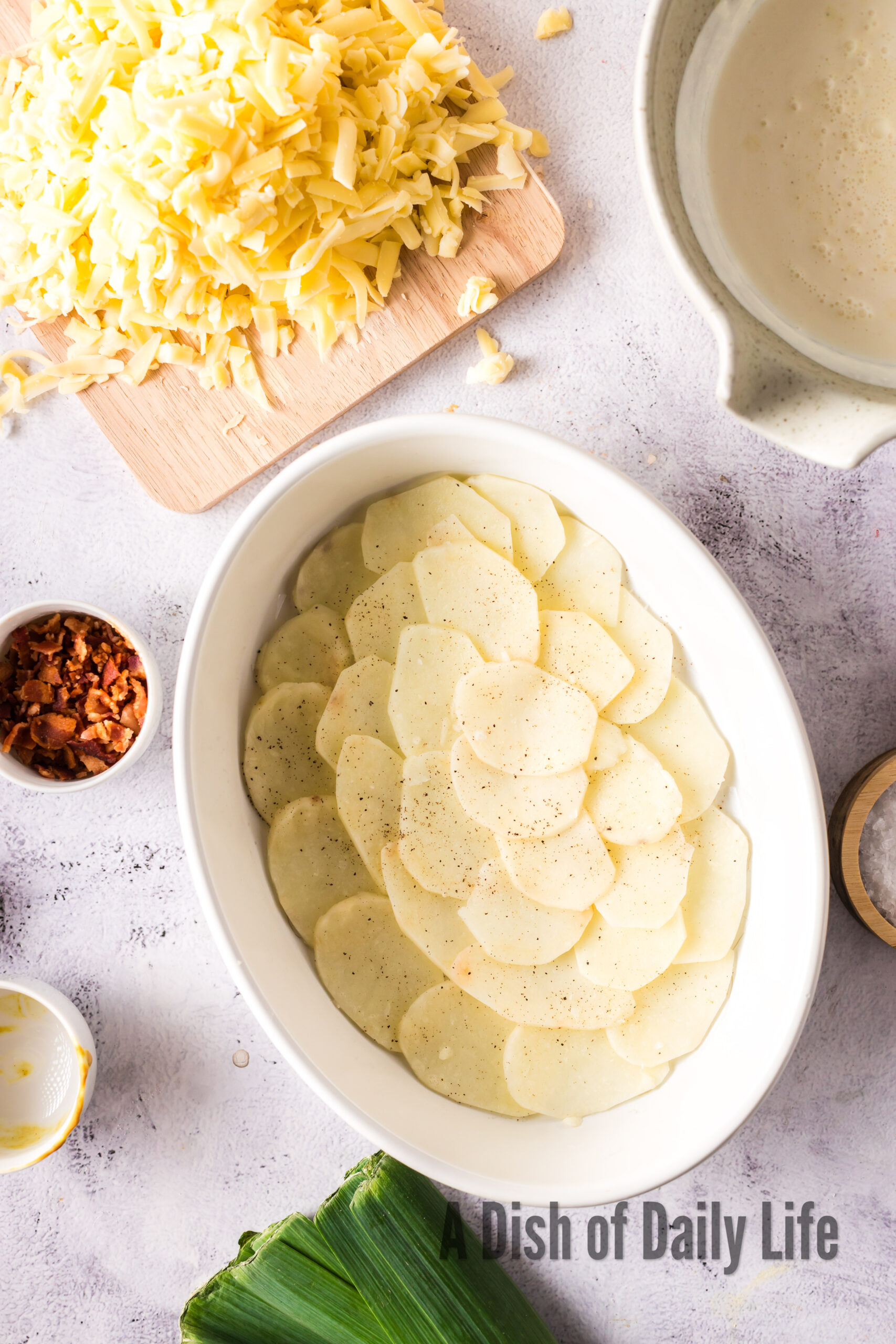sliced potatoes in the bottom of a casserole dish.