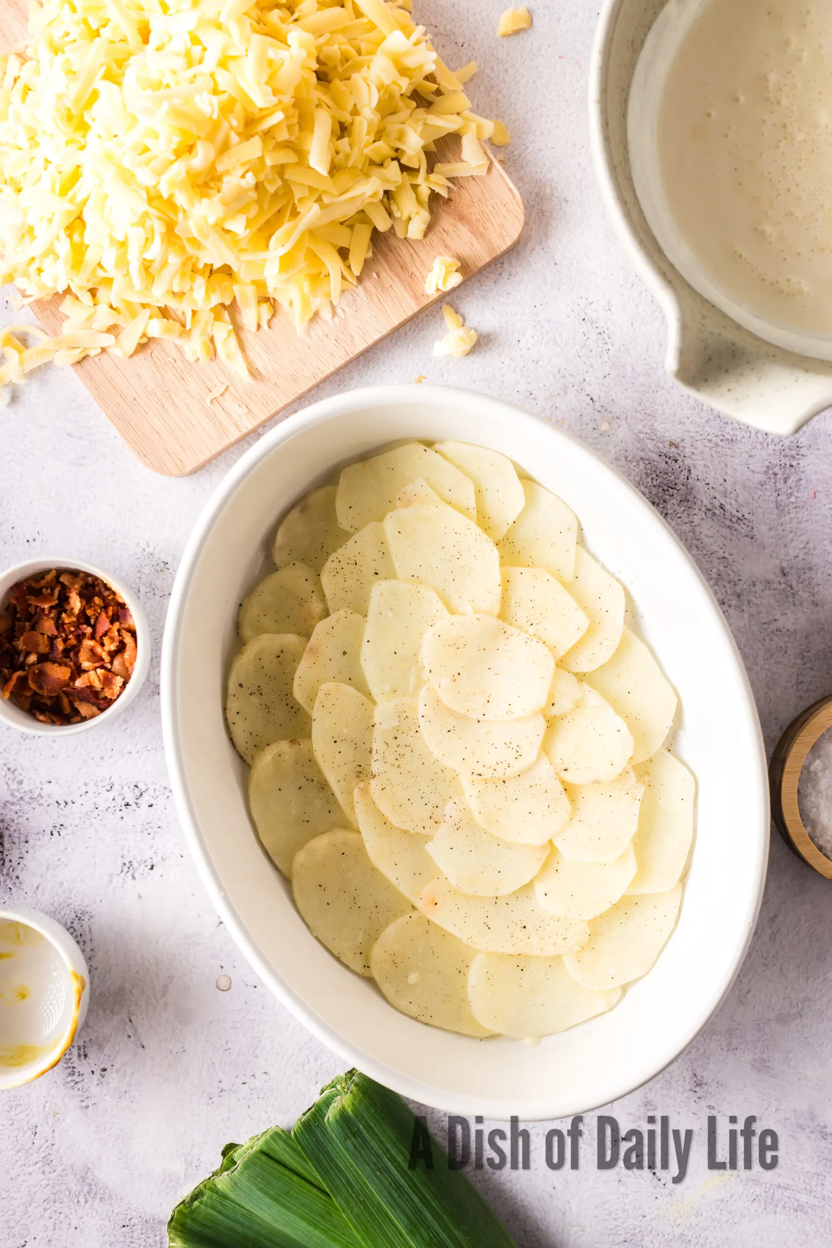 sliced potatoes in the bottom of a casserole dish.