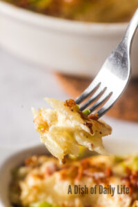 Fork scooping a portion of potatoes out of casserole dish.