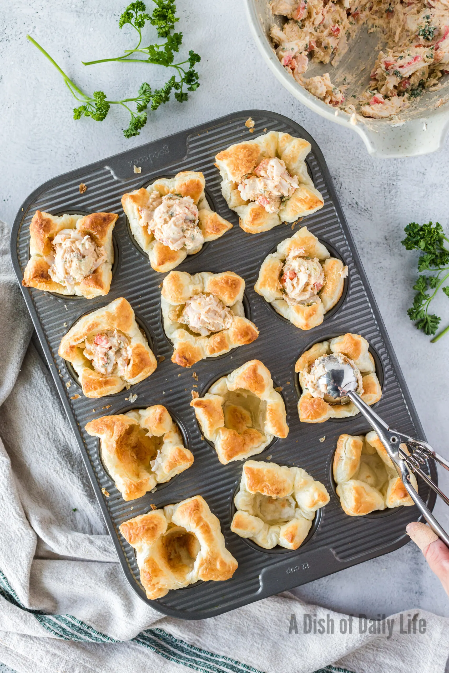 Filling each baked puff pastry shell with crab filling