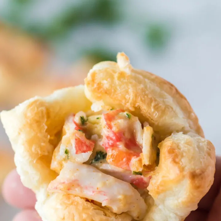 close up of a hand holding a crab puff appetizer.