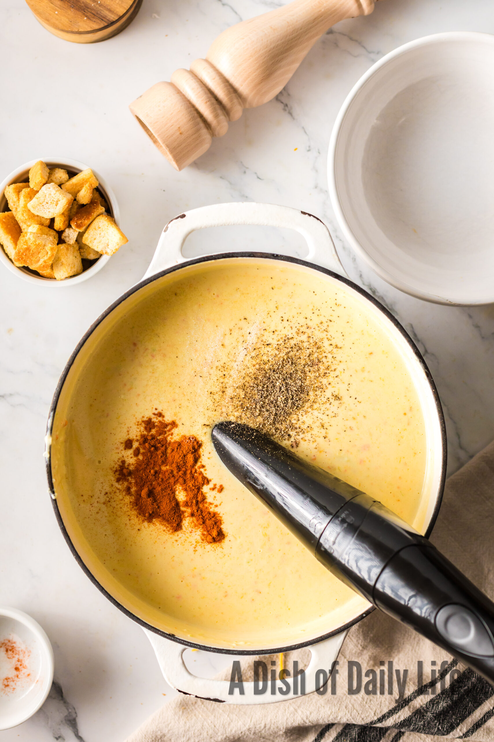 A hand blender used to blend up veggies, cheese and spices to a creamy soup.