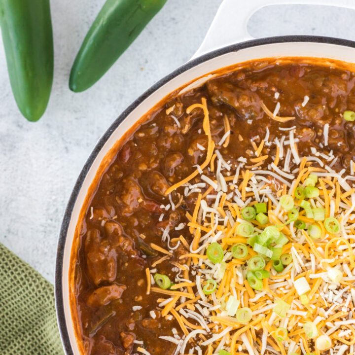 chili in pot topped with a pile of cheese and green onions