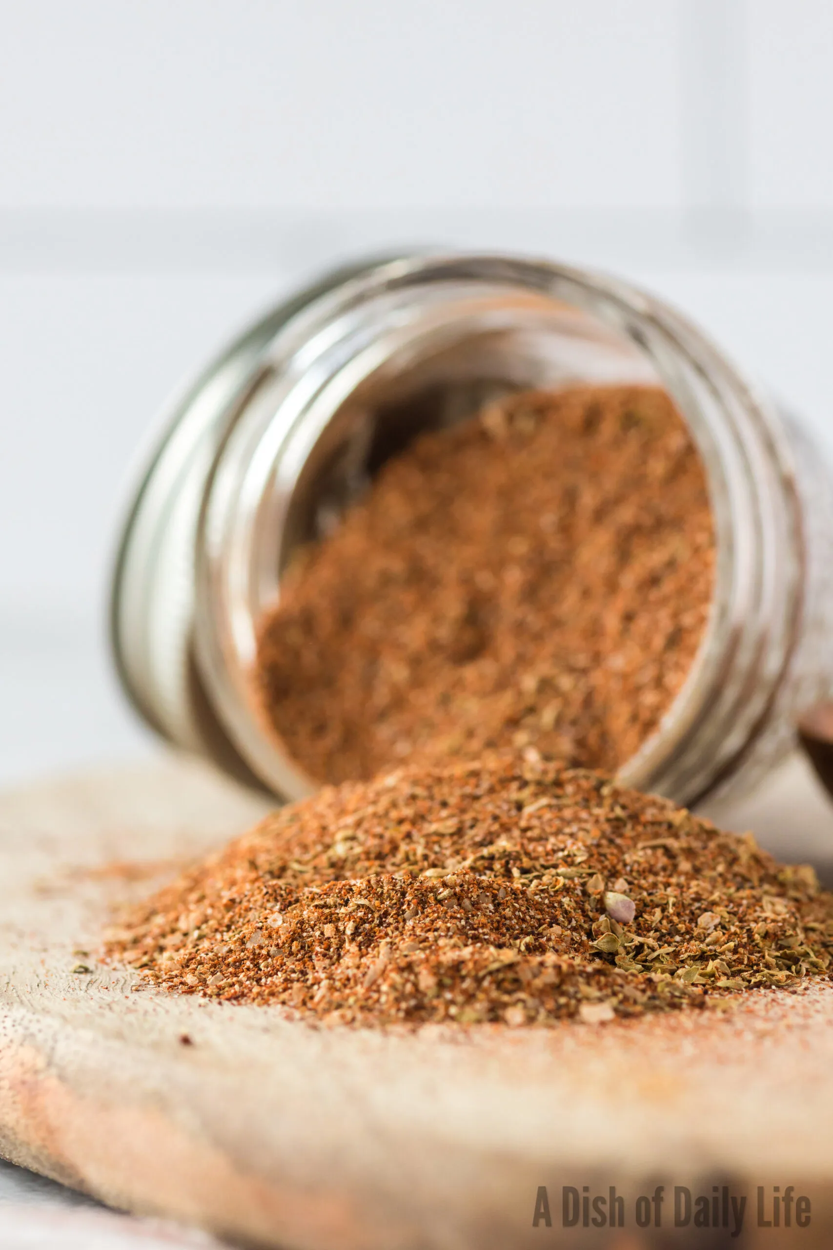 side view of jar of seasoning tipped on its side with seasoning falling out.