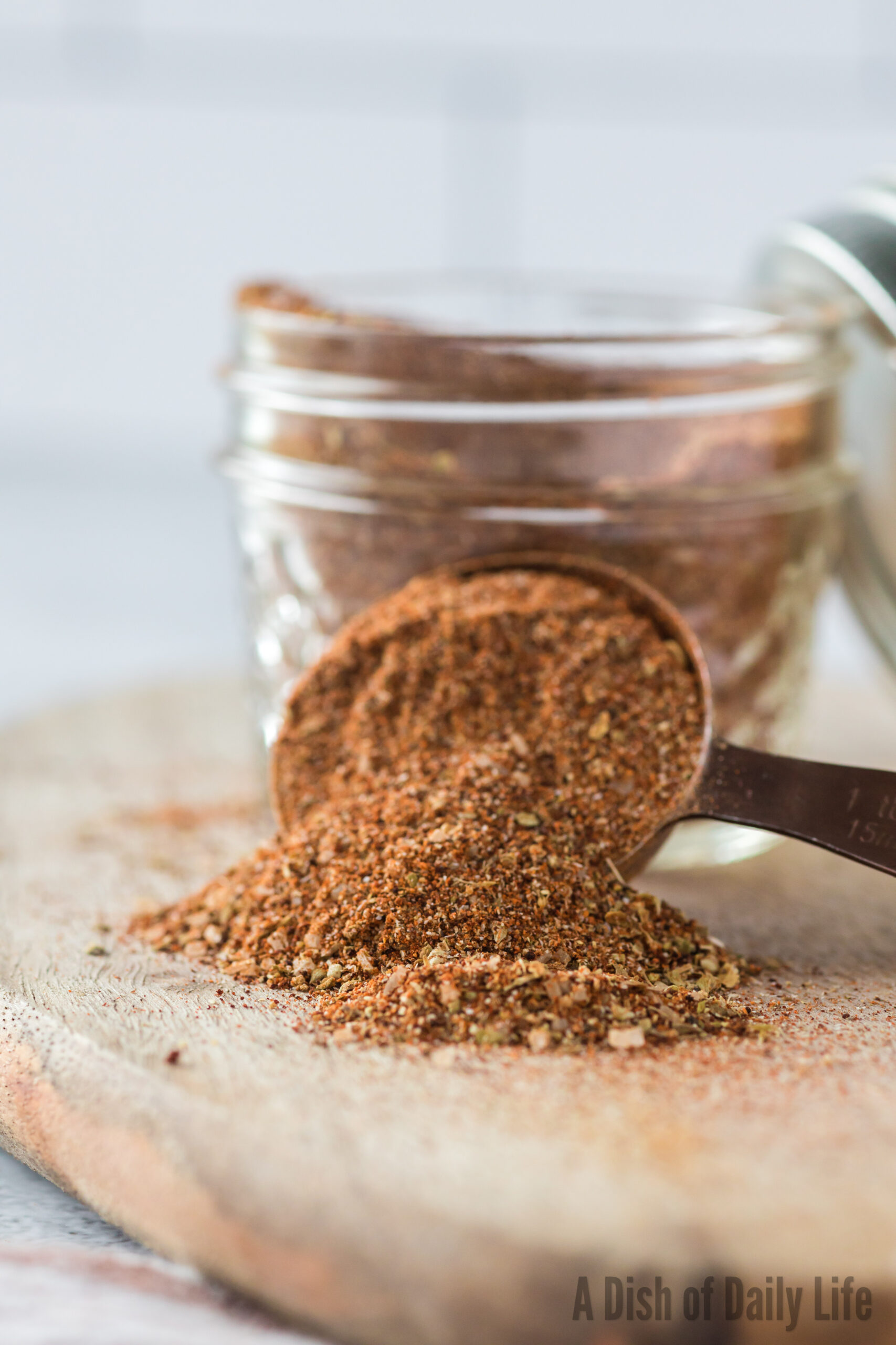 A tablespoon full of fajita seasoning propped up against a jar.