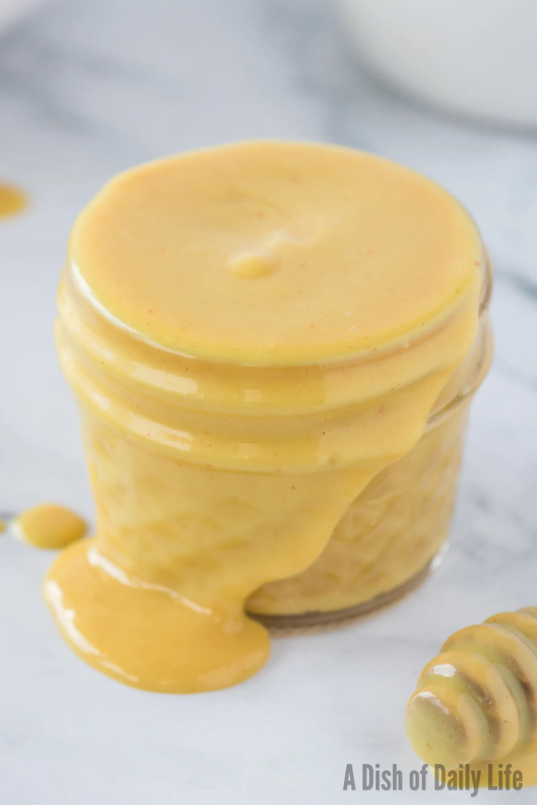 A small jar of overflowing honey mustard dressing