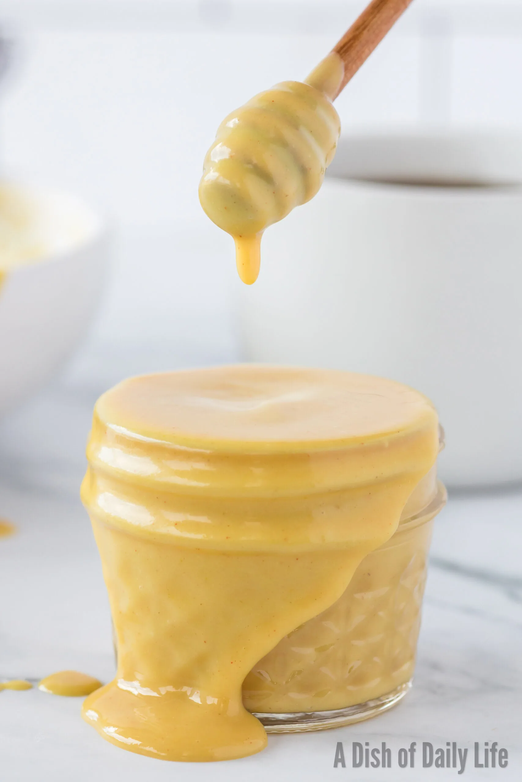 Honey wand held above honey mustard