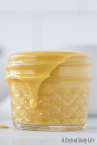 side view of honey mustard in jar with a little dripping down the side