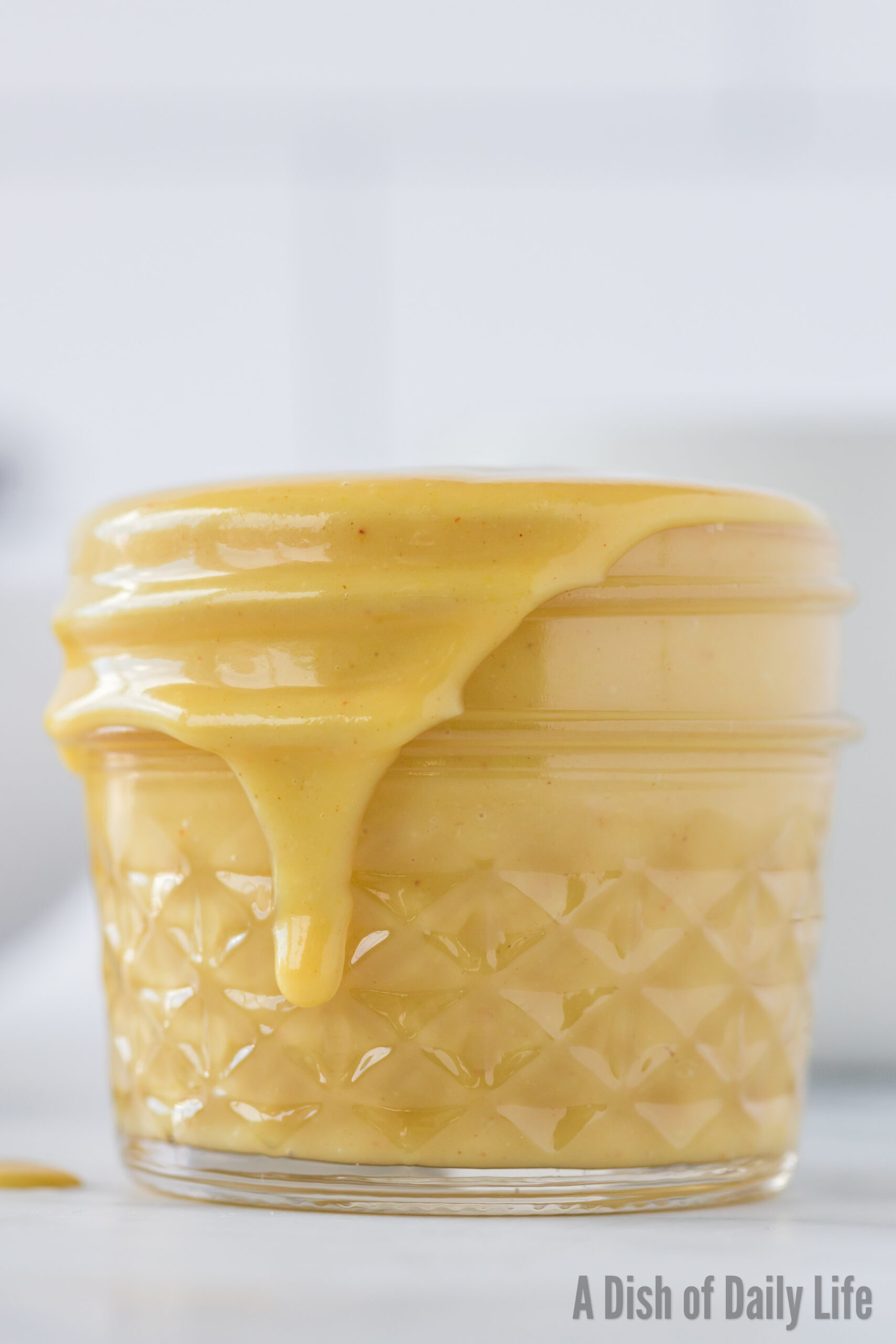 side view of honey mustard in jar with a little dripping down the side