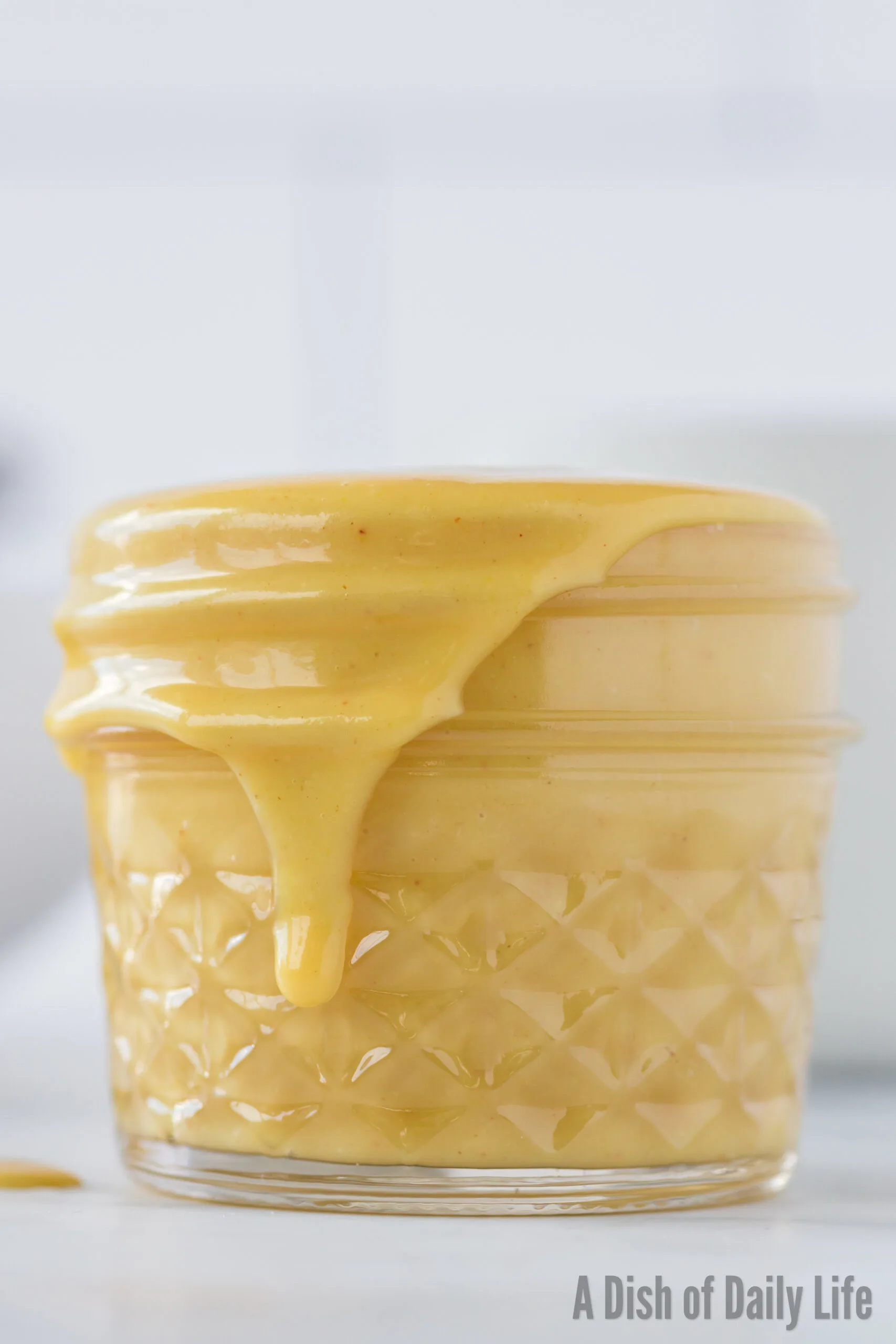 side view of honey mustard in jar with a little dripping down the side