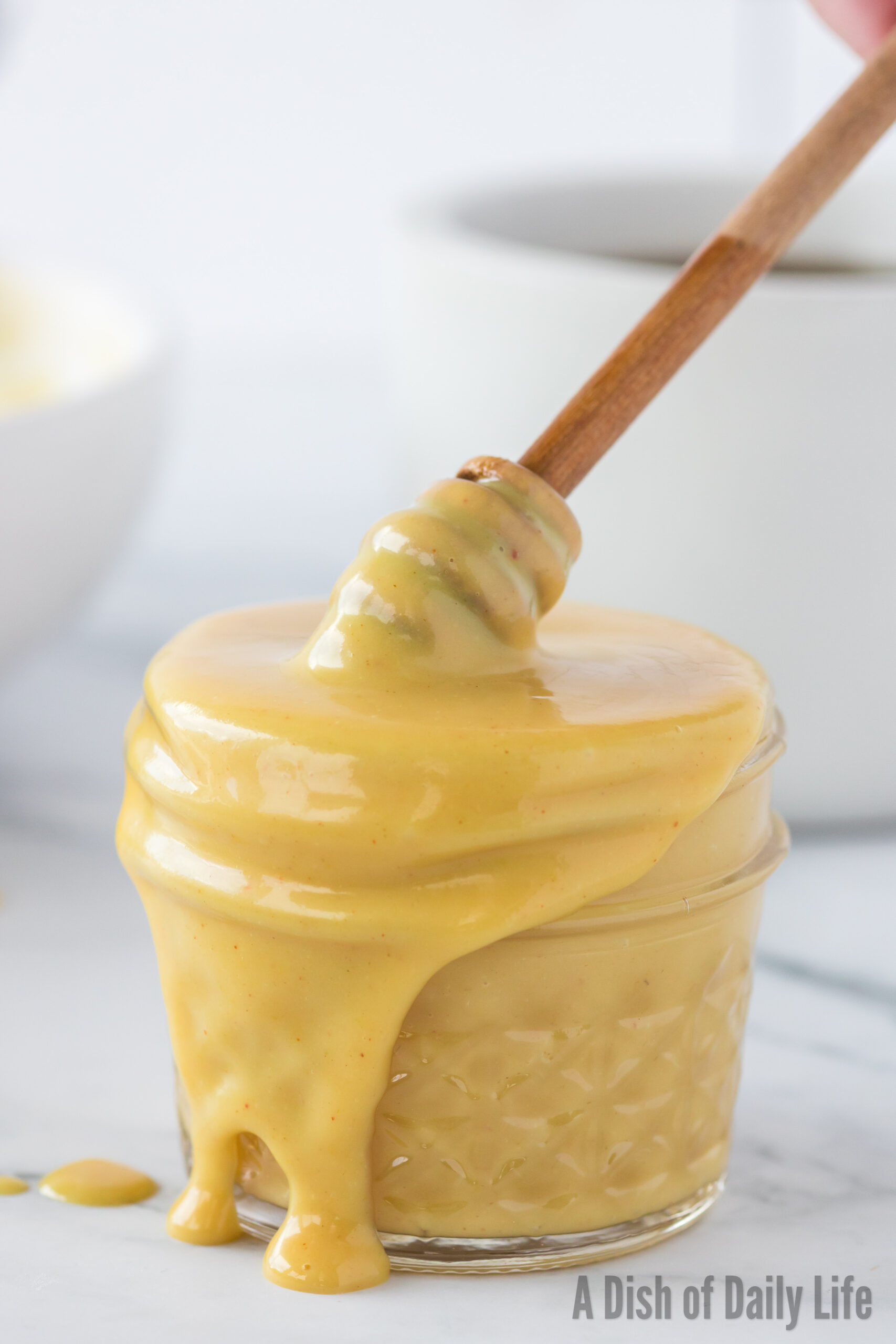 side view of honey mustard in jar with honey wand dipping into jar