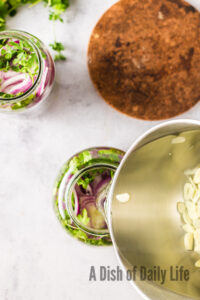 vinegar being poured into jar with onions.