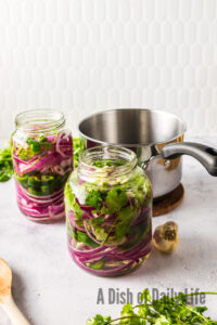 side view of two jars with onions and vinegar.