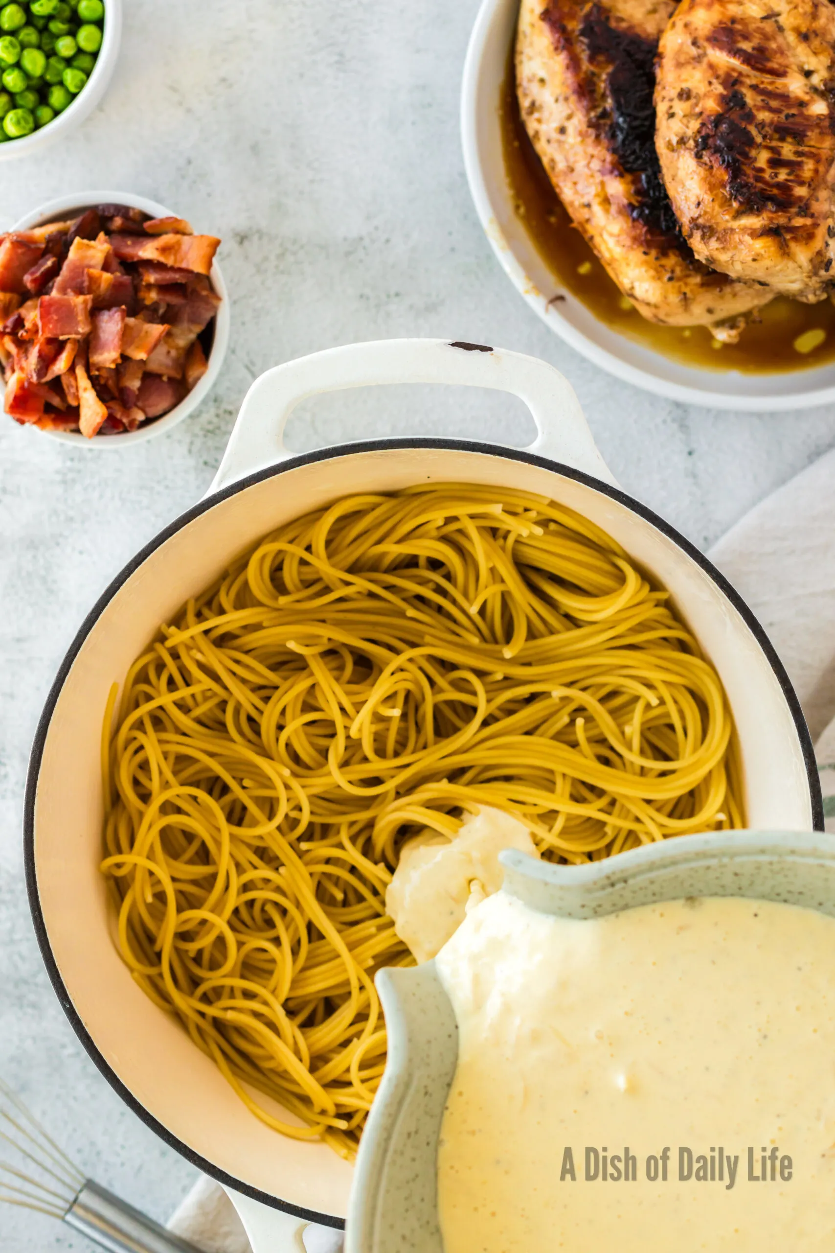 eggs, parmesan cheese, heavy cream, salt and pepper mixed up in a bowl and being poured over cooked spaghetti noodles.