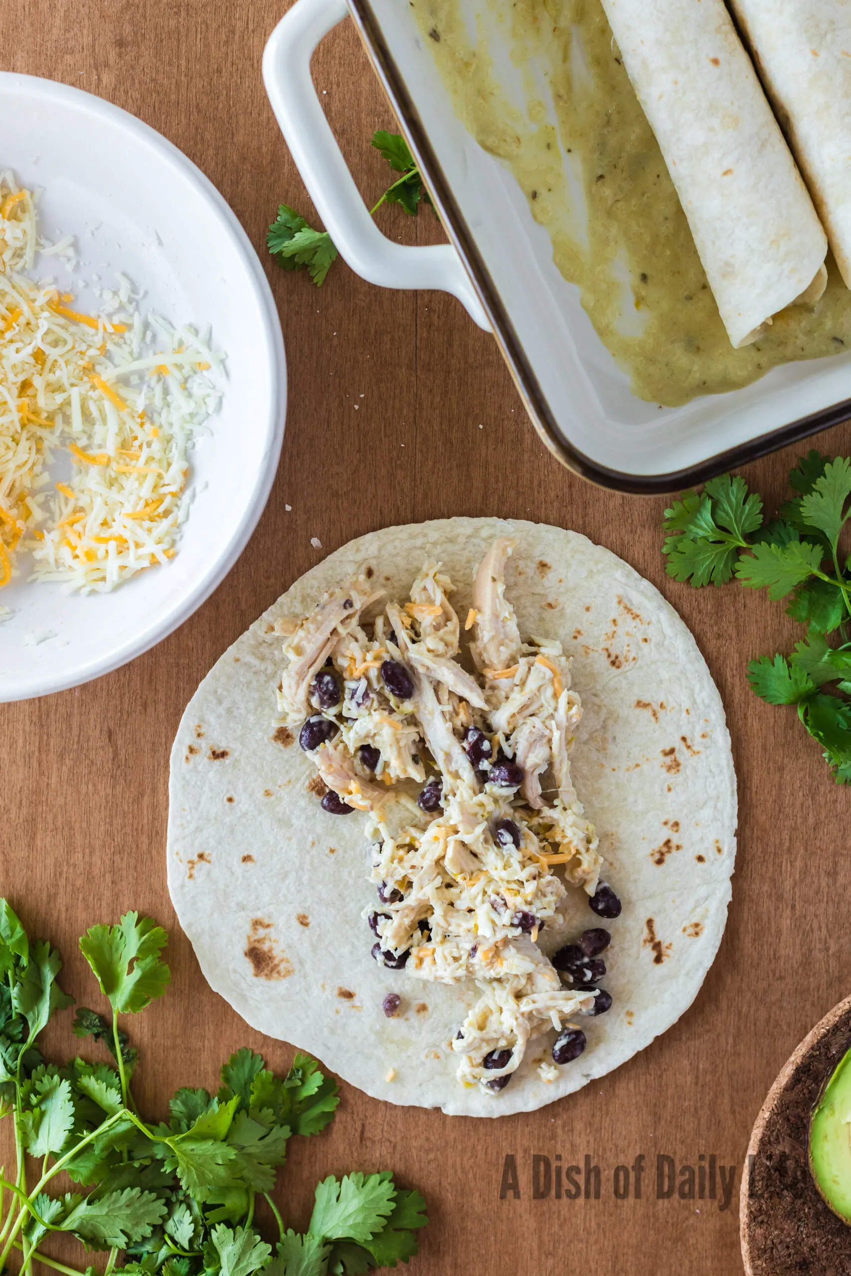 enchilada filling in a tortilla, ready to be rolled and added to casserole dish