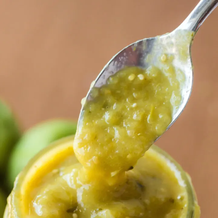 spoon scooping a portion of green chile sauce out of jar