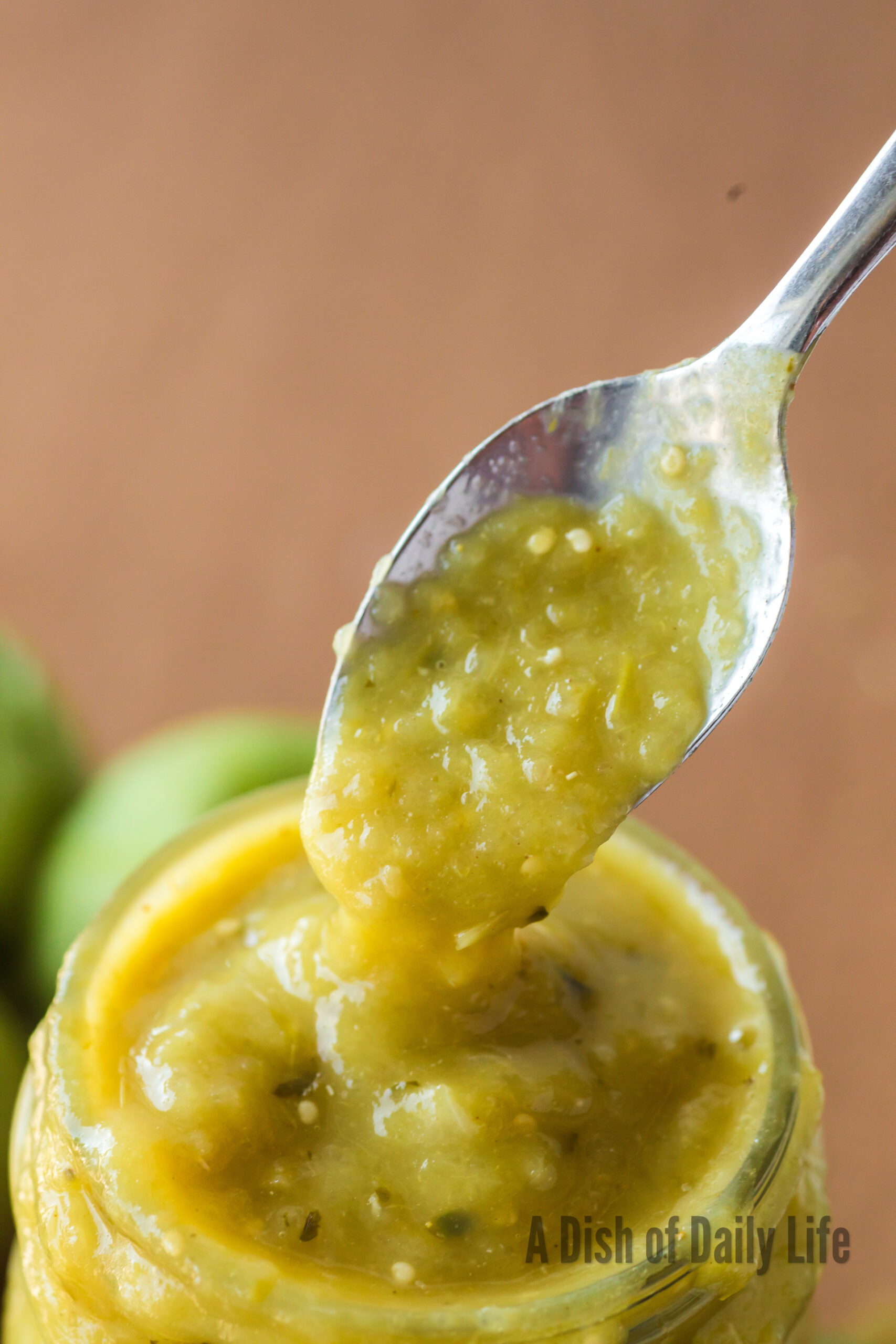 spoon scooping a portion of green chile sauce out of jar