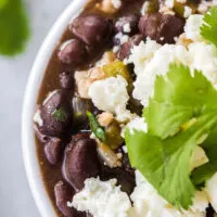 a bowl of mexican black beans with cheese and cilantro on top